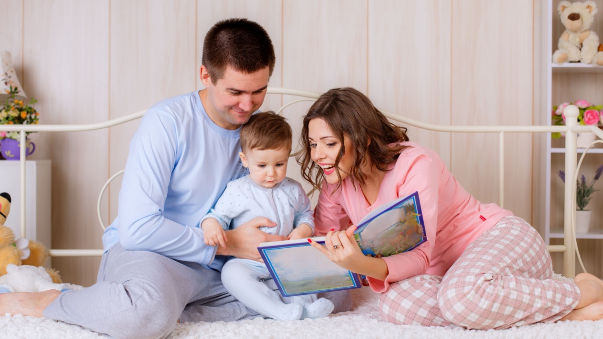 happy parents read a book your child in the nursery.