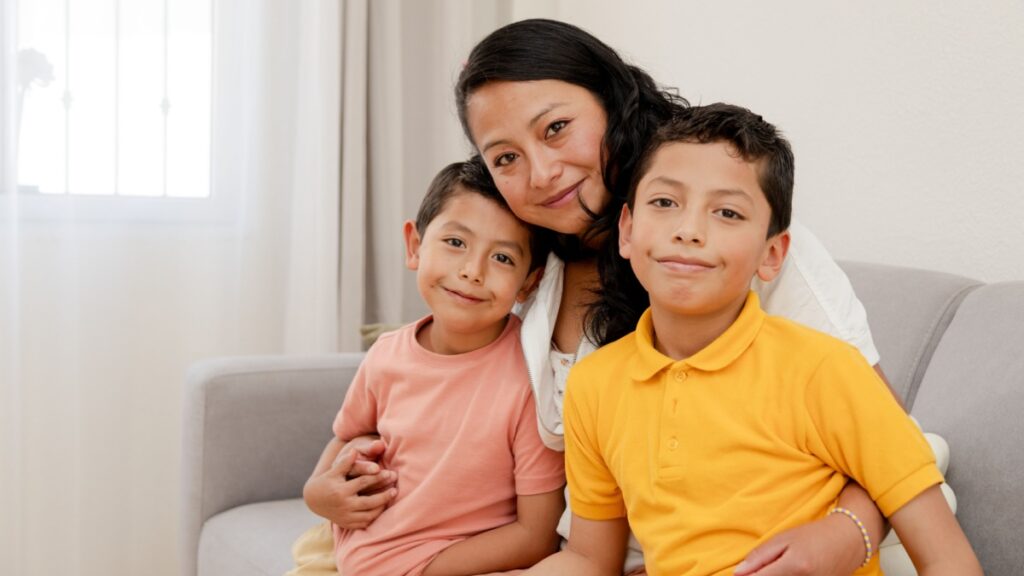 Portrait of mom and children at home-mom hugging hers two children in the living room of her house-single mother with her children-happy little family-Hispanic family.