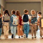 Back to school. A group of schoolchildren with backpacks walk along the school corridor during recess. Education and science concept..
