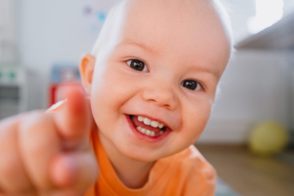 Portrait of a playful curious toddler. Cutest little girl smiling and looking at camera. Happy baby having fun. Lifestyle photography. Family at home.